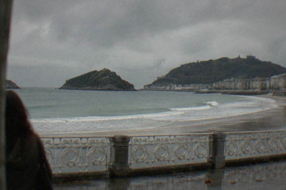 Rain clouds over La Concha bay in San Sebastián with white rollers breaking on the sand