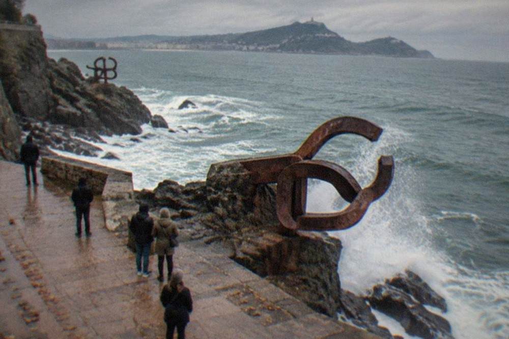 Waves breaking against the rocks at the Peine del Viento sculptures on a grey autumn day
