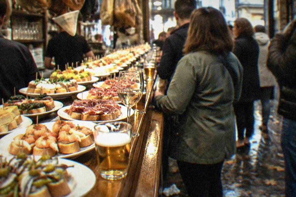 People standing at a pintxo bar counter in the Old Town of San Sebastián in the early evening