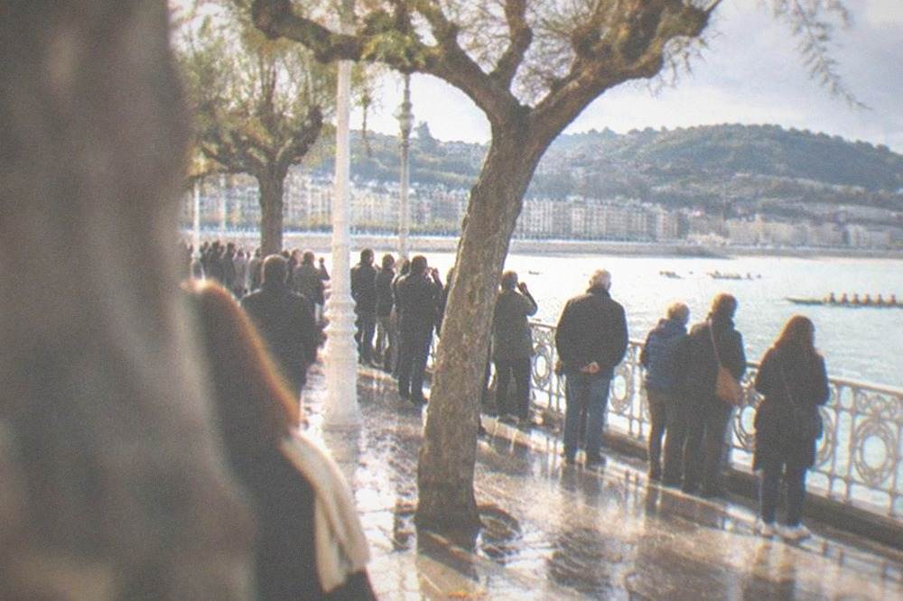 Crowds gathered along the La Concha promenade watching a rowing regatta on a sunny afternoon