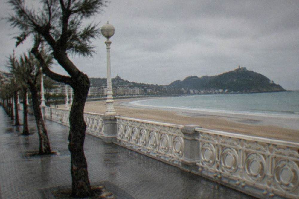 La Concha beach curving along the bay with the promenade railing and island in the distance