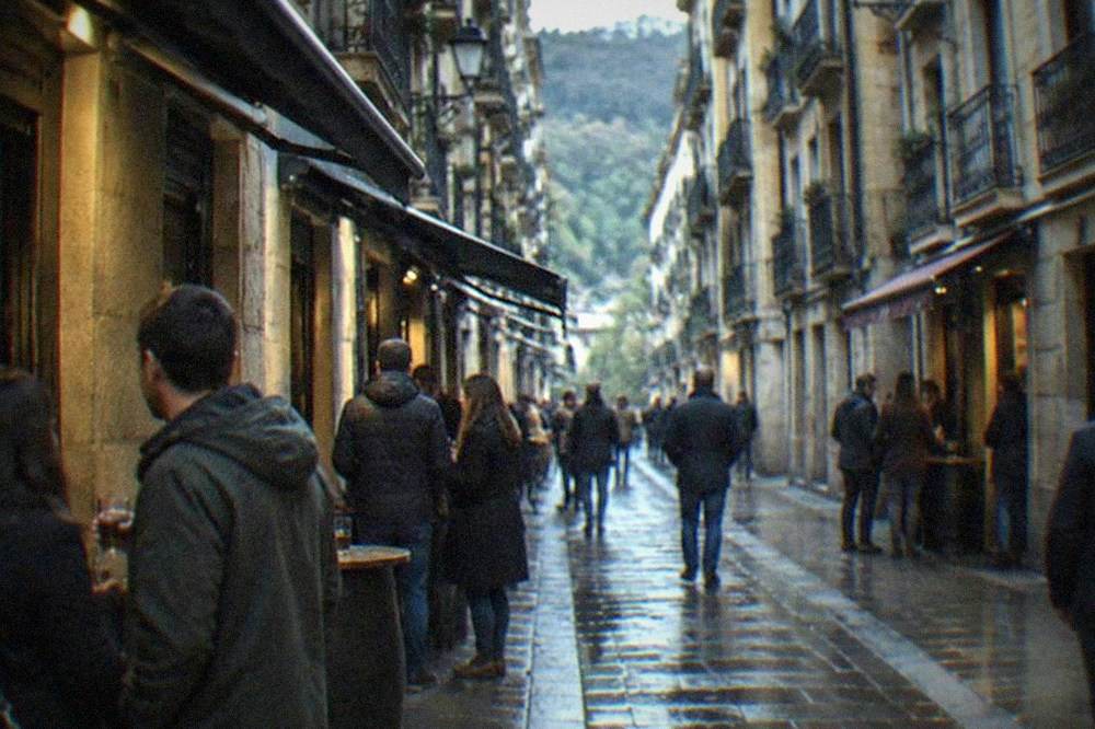 Narrow old town street in San Sebastián with tall buildings and bar awnings