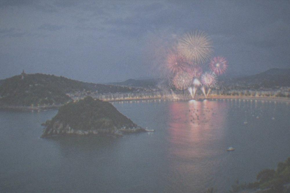 Fireworks bursting over La Concha bay watched from the seafront at night