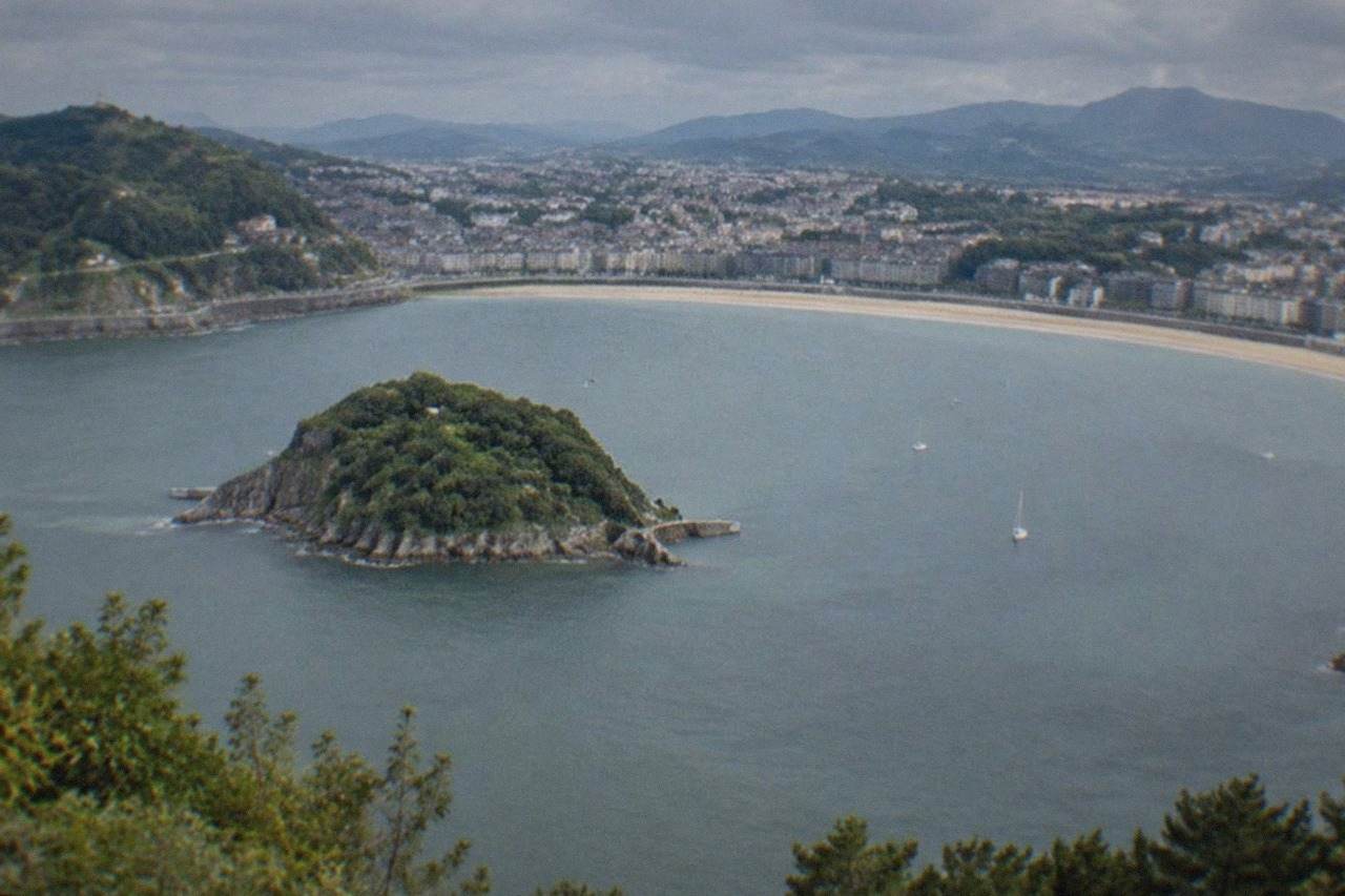 La Concha bay in San Sebastián seen from a high viewpoint, with the beach curve and Santa Clara island below