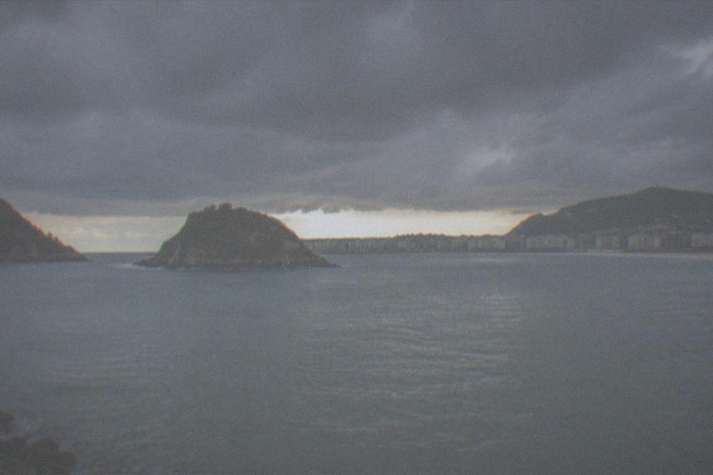 Dramatic storm clouds over La Concha bay with a band of clear light at the horizon