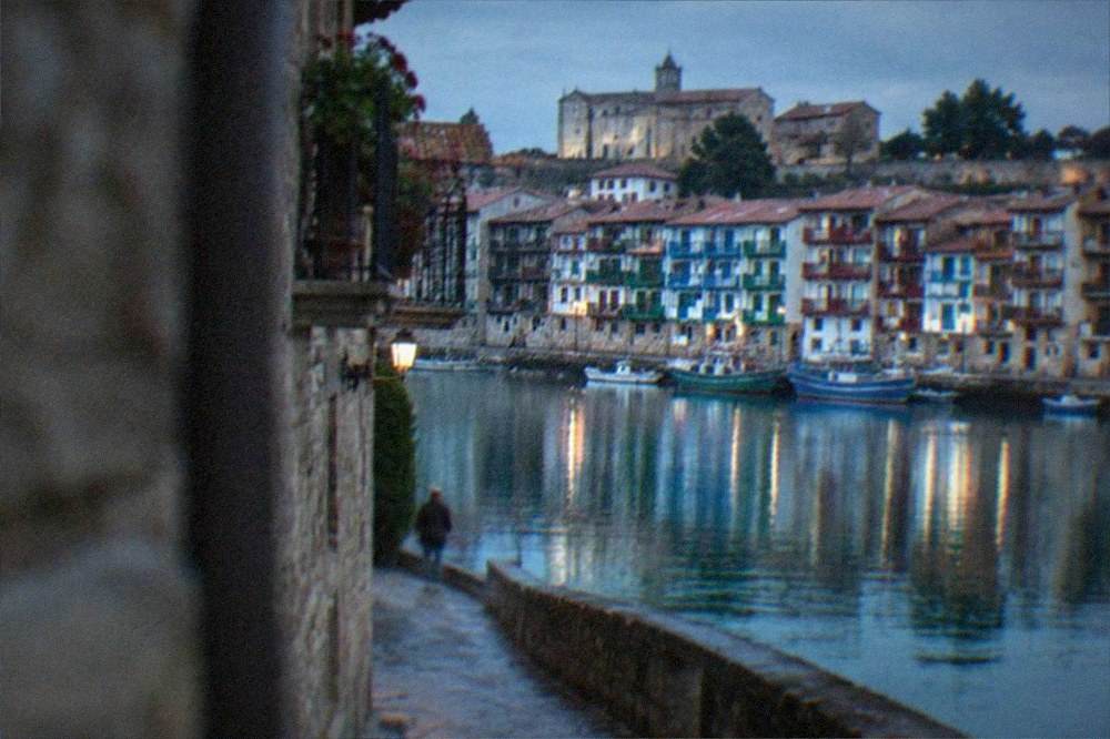 The coloured harbour houses of Hondarribia reflected in still water at dawn