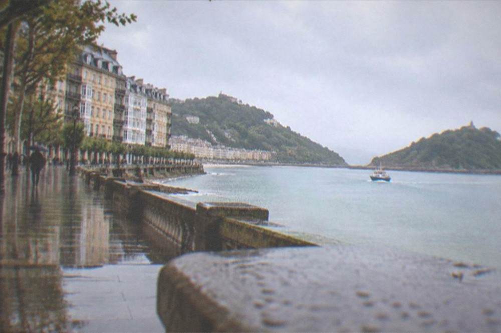 A small boat crossing a calm bay toward a green island