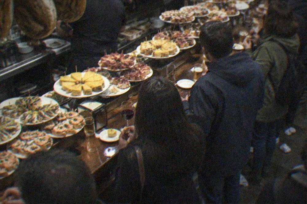 People eating pintxos at a crowded bar counter in the San Sebastián Old Town