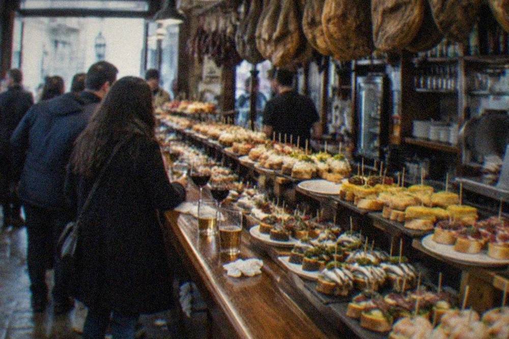 A busy pintxo bar counter in the Old Town of San Sebastián lined with small servings on bread