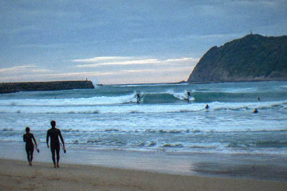 Waves breaking at Zurriola beach in San Sebastián with surfers in the water