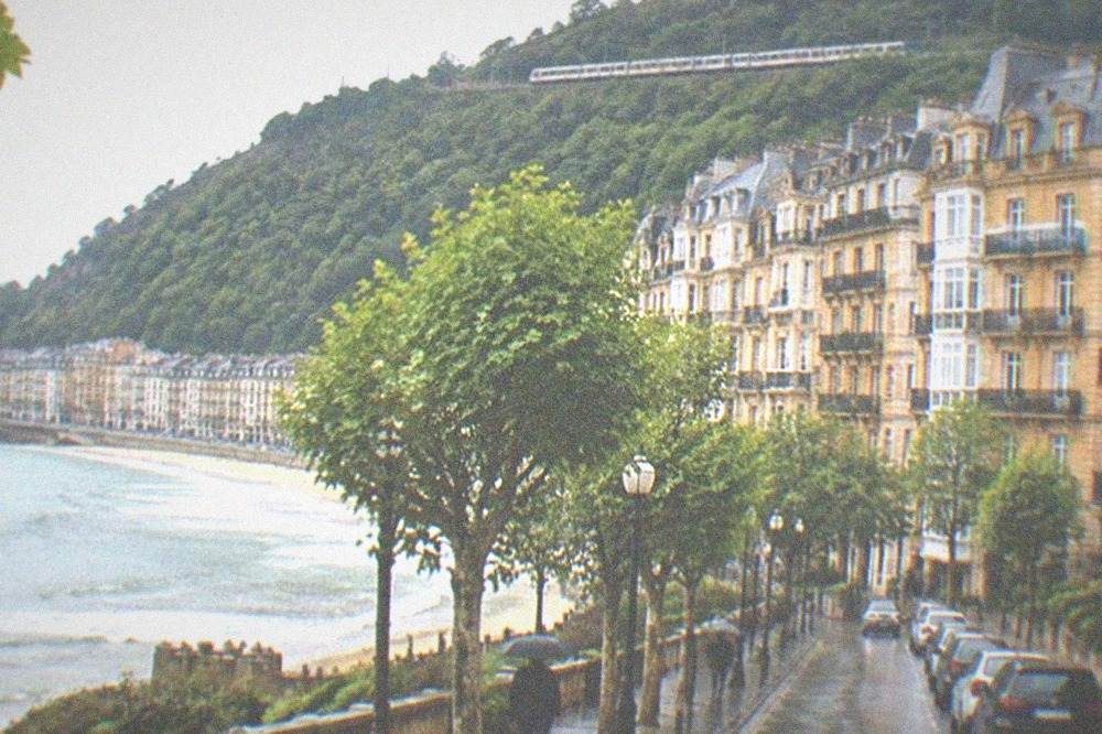 A train travelling along the green hills of the Basque coast