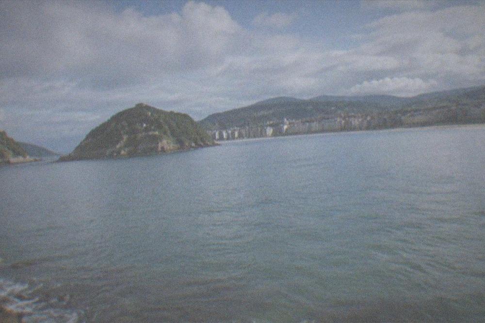 Clouds and sunshine over the bay of La Concha with green hills behind the city