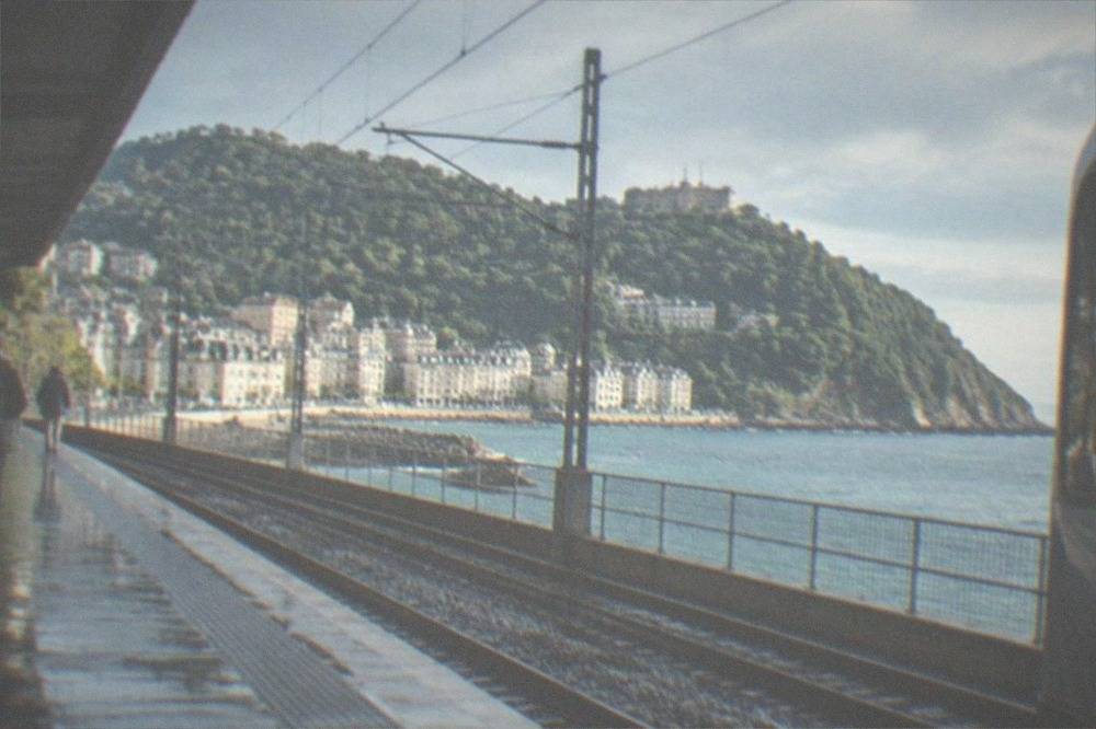 A coastal train platform near San Sebastián with the green hills of the Basque coast behind it