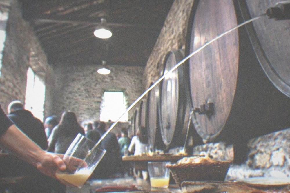 A cider house dining room in Gipuzkoa with diners catching cider from a barrel