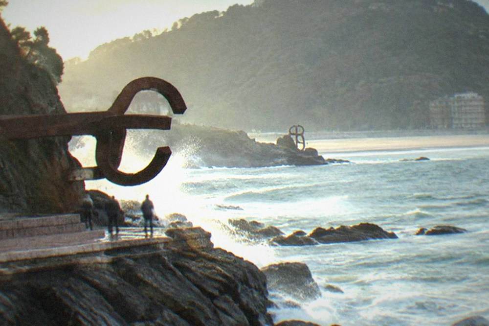 Ondarreta beach at low tide with the Peine del Viento sculptures visible at the far end