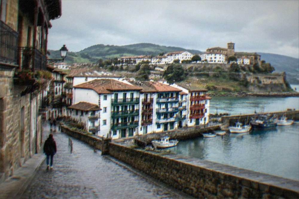 The white walled old town of Hondarribia with green hills behind under a bright sky