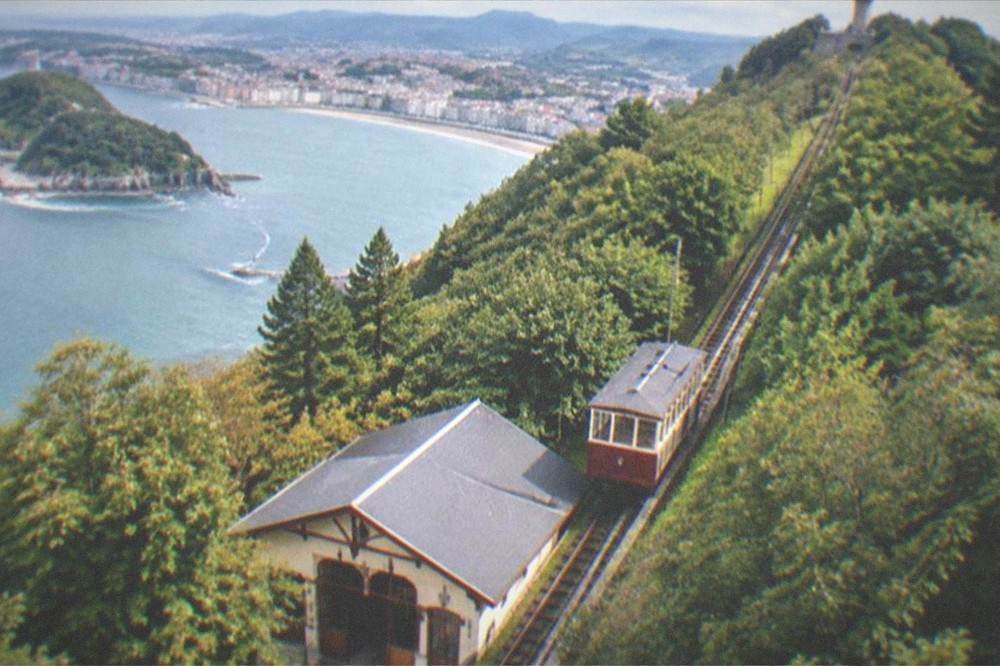 The wooden funicular car of Monte Igueldo at the lower station with the tower on the hill above