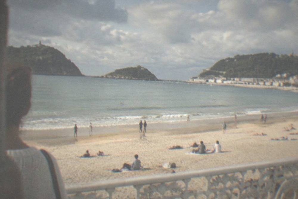 Sunbathers on La Concha beach in San Sebastián under a partly cloudy summer sky