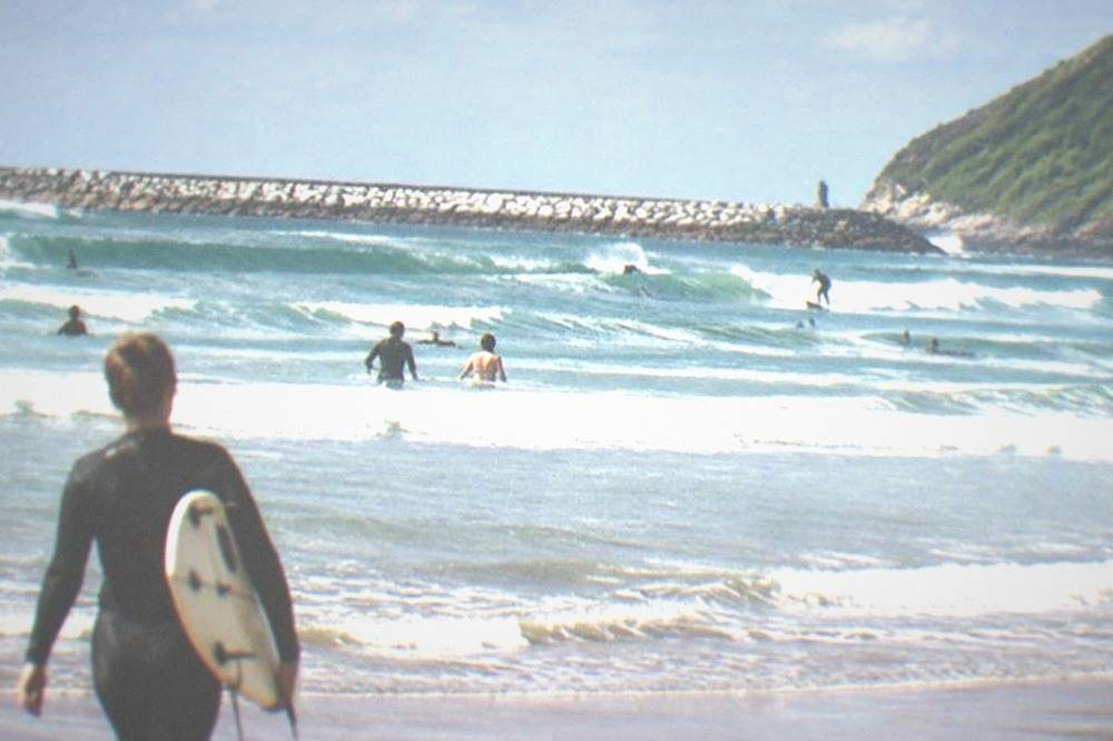Swimmers in the water at Zurriola beach in San Sebastián on a summer afternoon