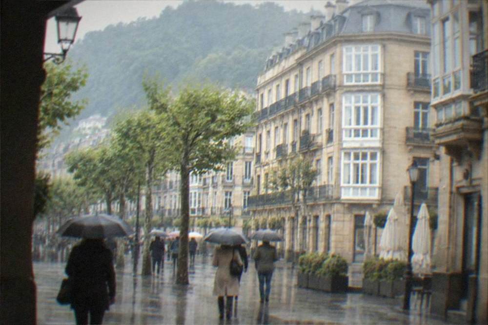 People with umbrellas walking through a wet street in the Old Town of San Sebastián