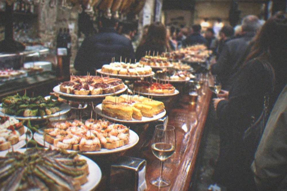 A crowded pintxo bar counter in the Old Town of San Sebastián on a rainy evening