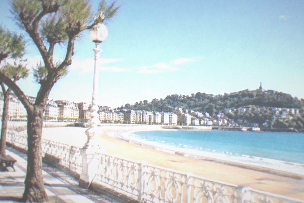 Wide sandy curve of La Concha beach with the bay promenade and Monte Igueldo behind