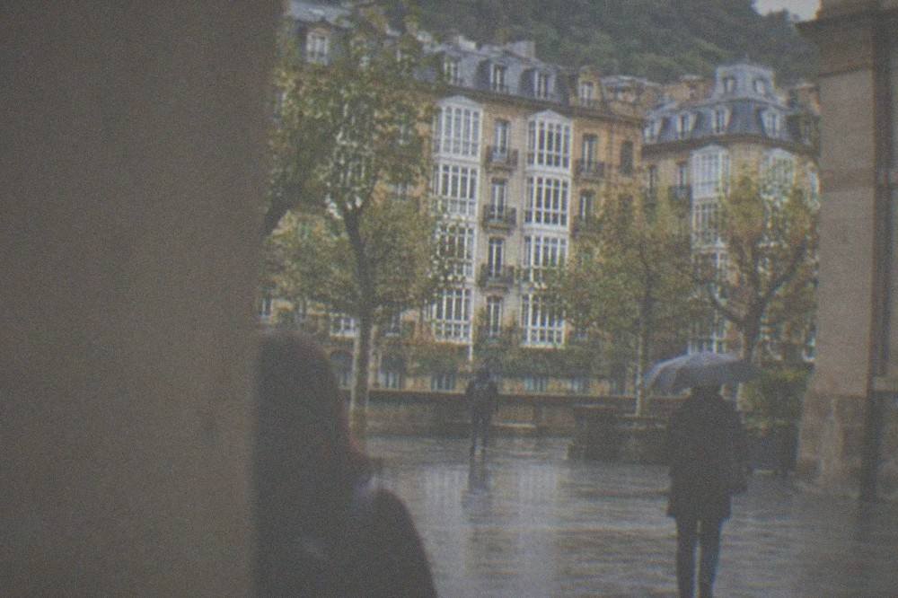 Visitors walking through the courtyard of a stone museum building in San Sebastián on a rainy afternoon