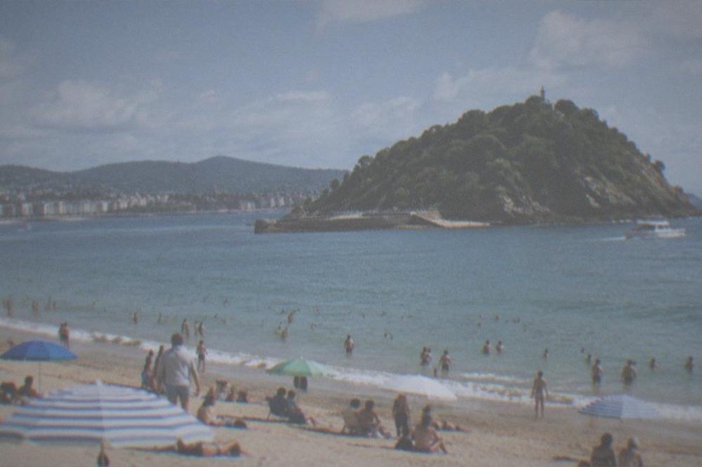 La Concha beach on a busy sunny August day with parasols and the island in the bay