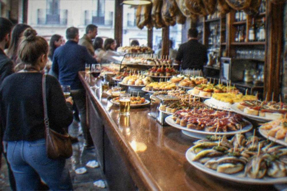 A pintxo bar counter loaded with small skewered dishes and plates in the Old Town of San Sebastián