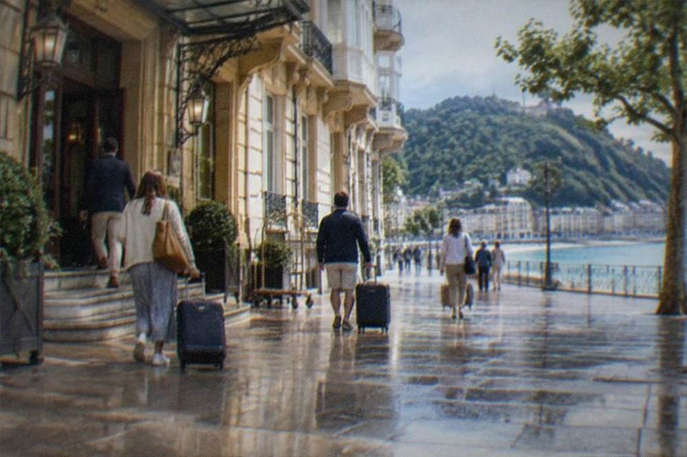 A hotel facade near the seafront of San Sebastián with people arriving with luggage on a summer evening
