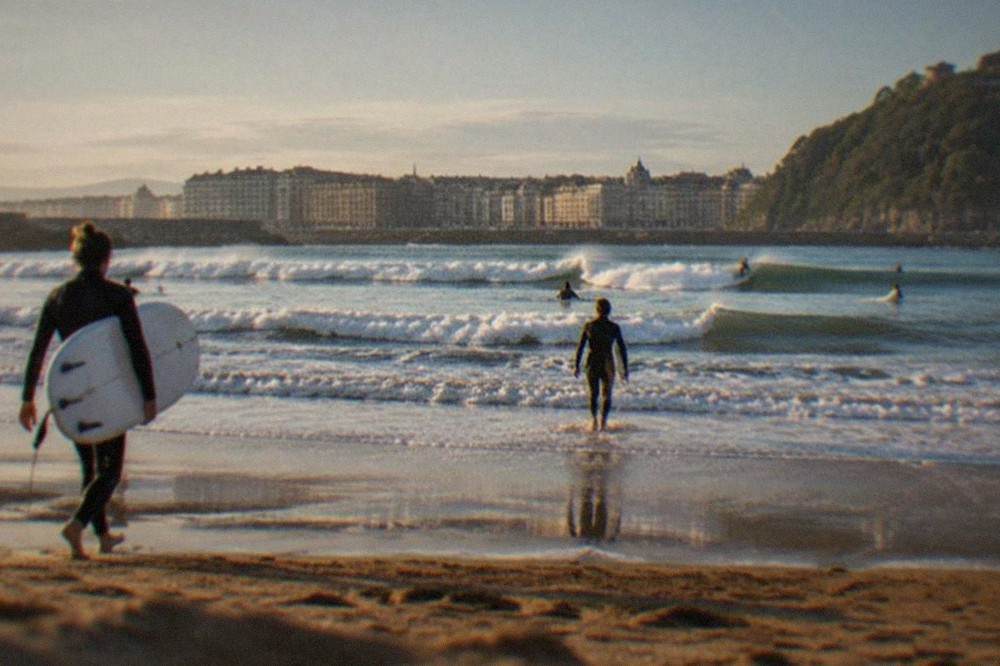 Waves breaking at Zurriola beach at dawn with the Gros district buildings behind