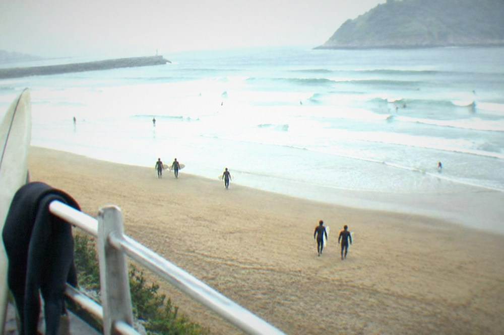 A wetsuit and surfboard leaning against a railing near Zurriola beach