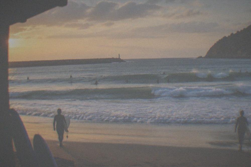 Surfers sitting on their boards waiting for a wave offshore at Zurriola beach
