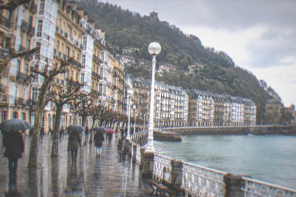 A walled fishing town beside a river mouth seen under clearing winter skies