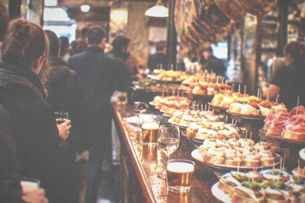 A crowded pintxo bar counter in the San Sebastián old town at evening
