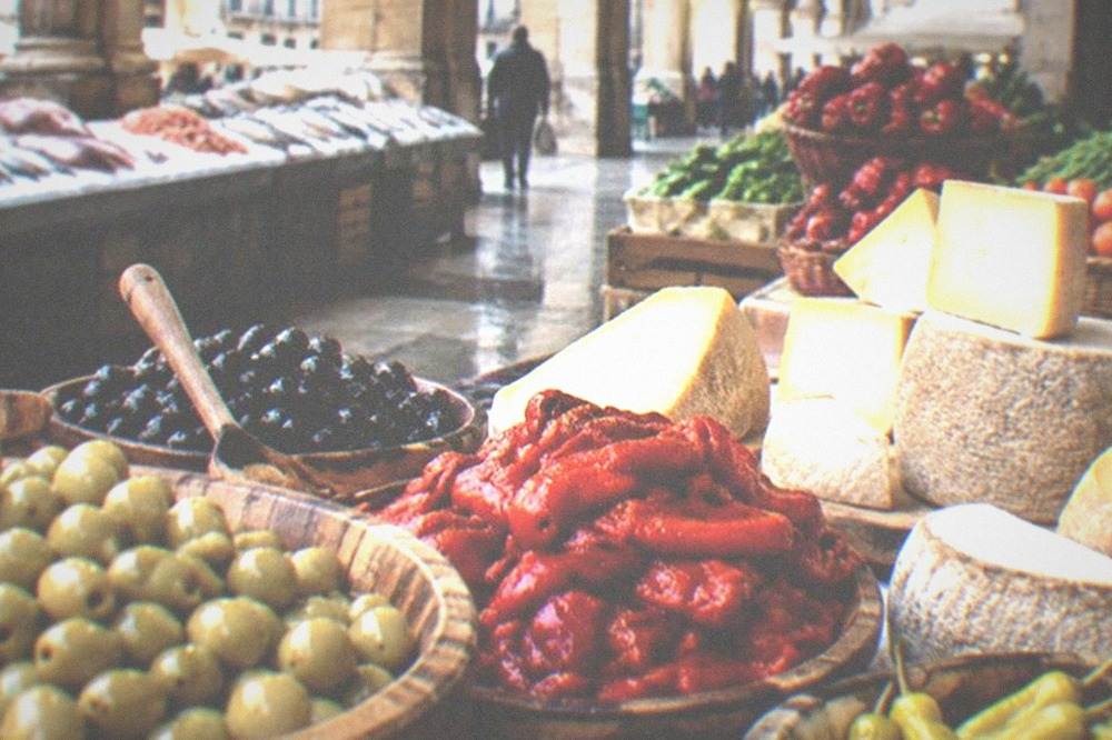 A market stall with olives, peppers and Basque cheese on display