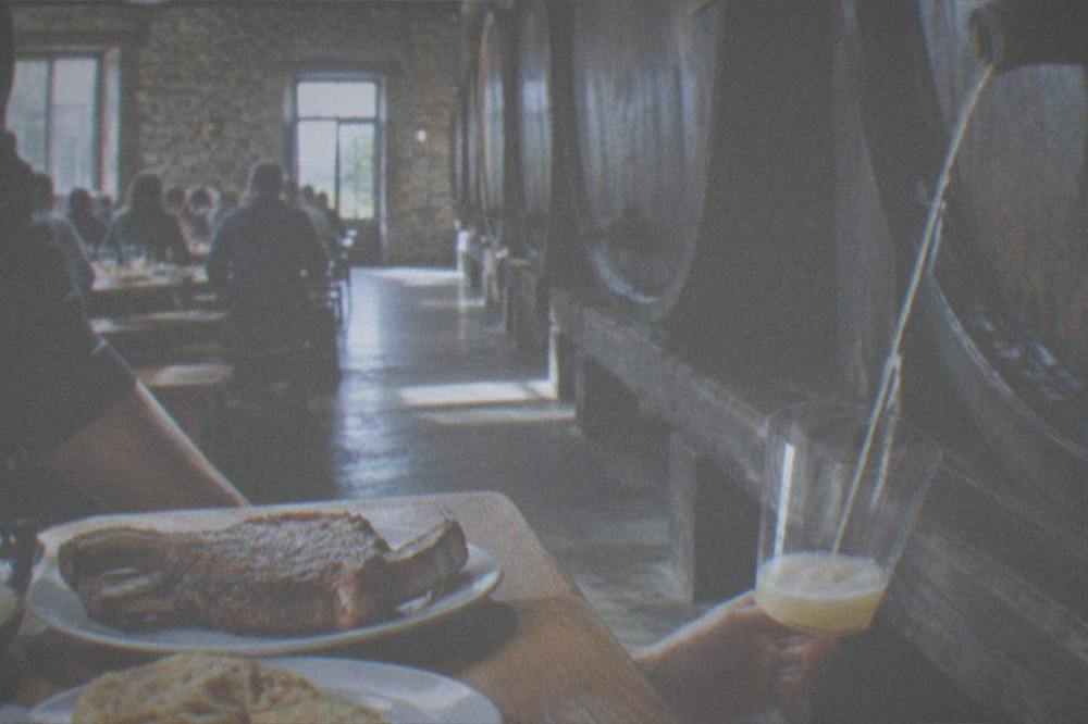 Cider streaming from a barrel into a glass held at a cider house in the Basque Country