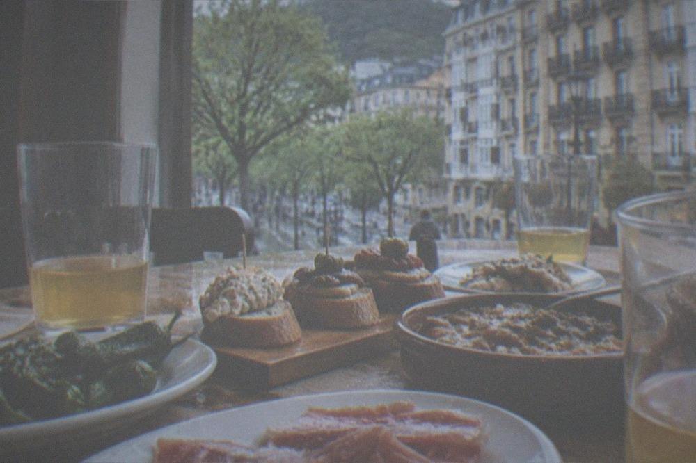 A table of shared Basque dishes in a San Sebastián restaurant with cider glasses