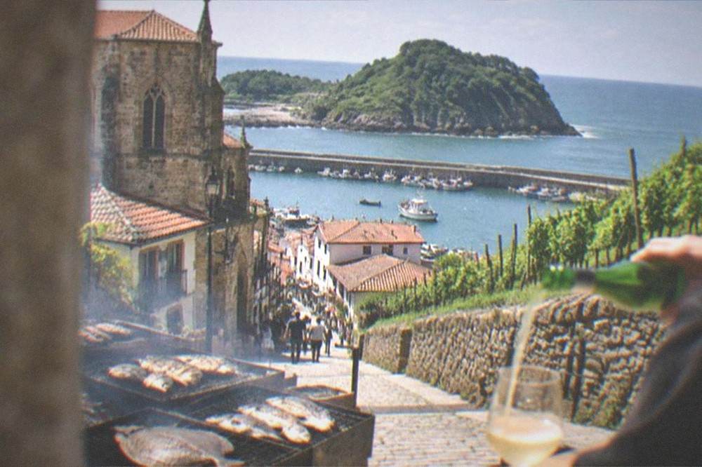 A glass of txakoli being poured from a height at a bar in San Sebastián