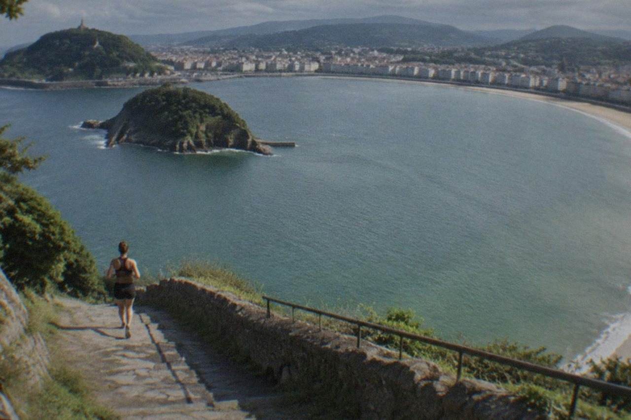 The curved sandy bay of La Concha seen from above with the city and green hills behind it