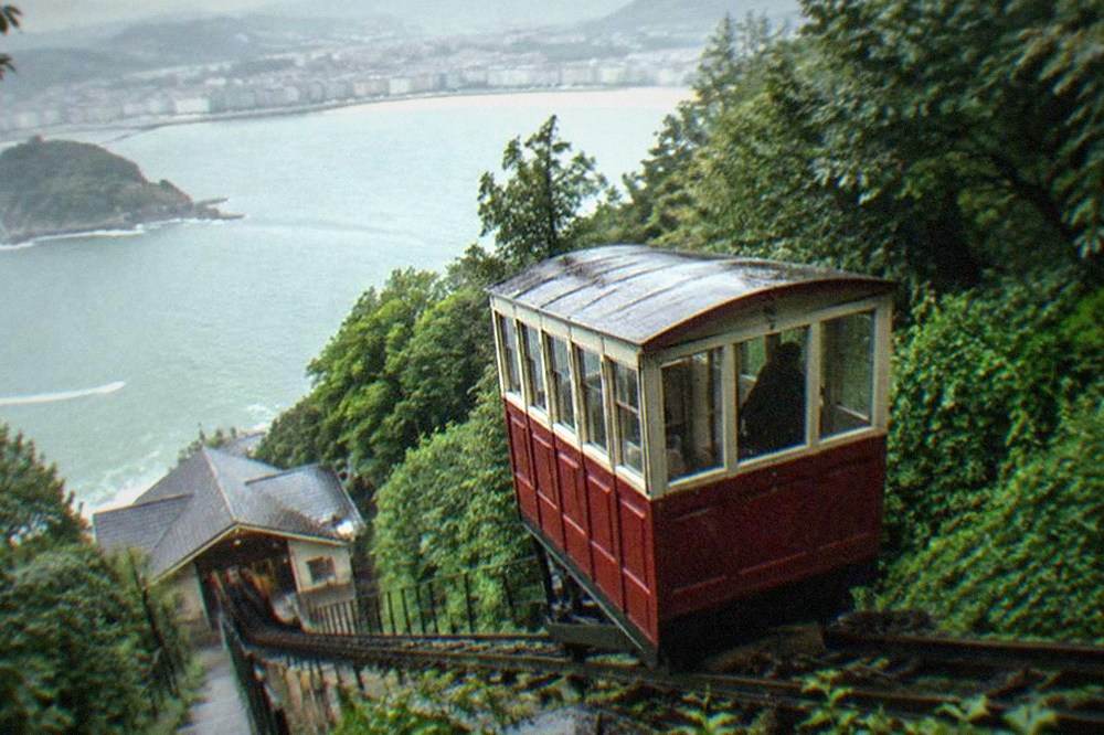 The wooden funicular car climbing the green slope of Monte Igueldo above the bay