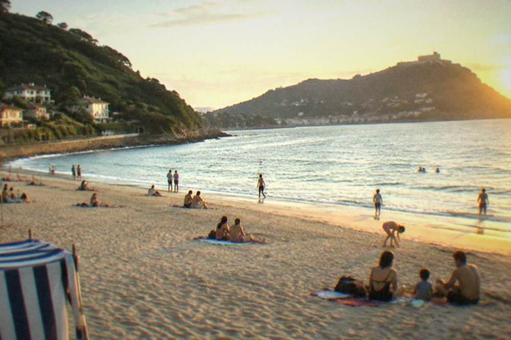 Ondarreta beach in the afternoon with families on the sand and Monte Igueldo in the background