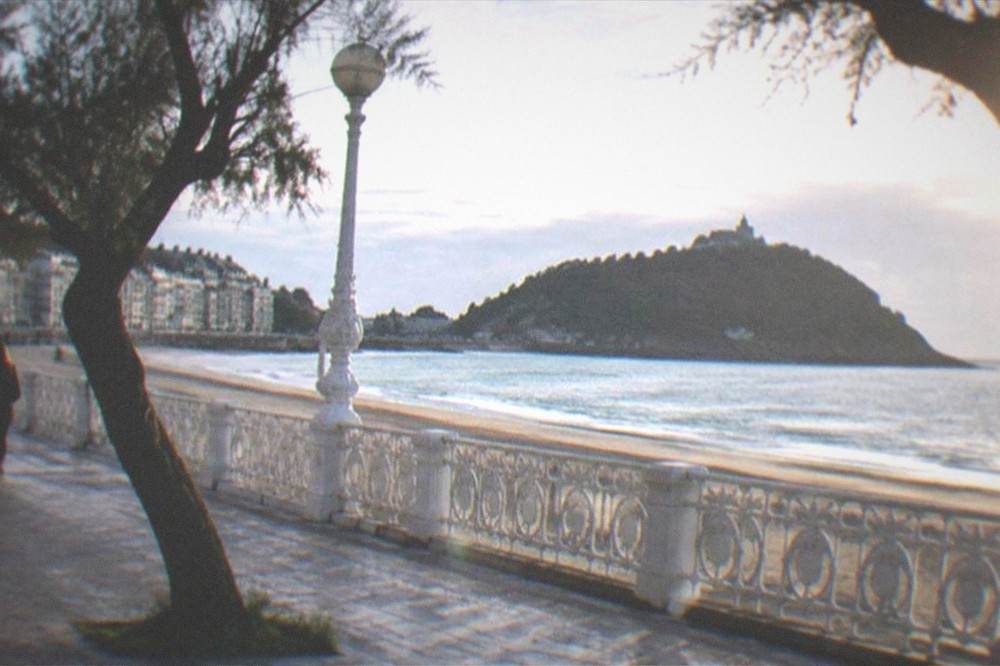 Morning on La Concha promenade with the railings, the sand and the island across the water