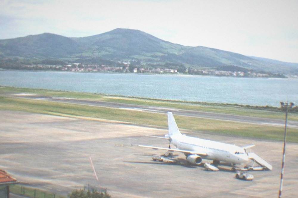 A small airport apron at dusk with hills behind the runway lights