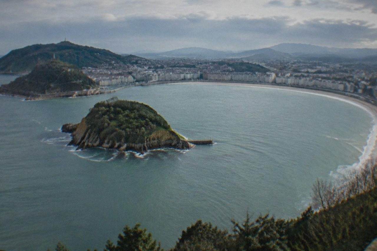 The curve of La Concha bay in San Sebastián seen from above, with the beach, the island and green hills