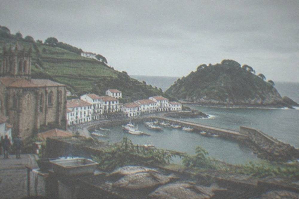 White houses of Getaria above a small fishing harbour with green hills behind
