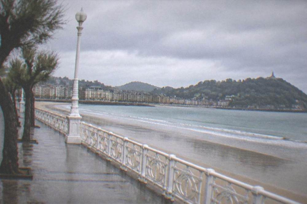 Rain clouds over La Concha bay with wet sand and empty promenade in San Sebastián