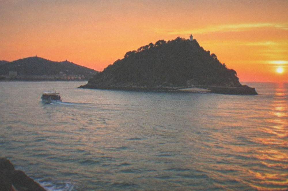 A sunset over La Concha bay with Santa Clara island dark against the orange sky