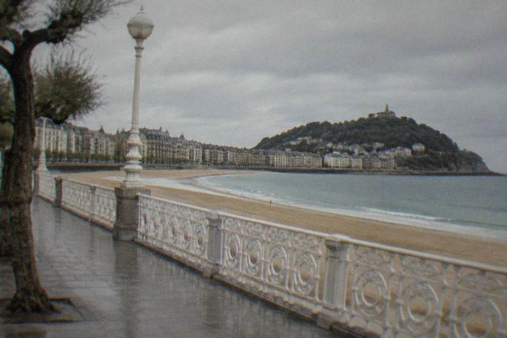 The white railing and balustrade of the La Concha promenade with the sandy beach and bay beyond