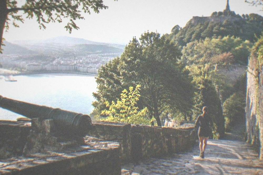 A stone fortification and statue on the wooded summit of Monte Urgull above the bay